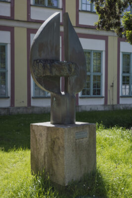 Zdjęcie pionowe wykonane na wprost, na którym znajduje się rzeźba o abstrakcyjnym charakterze wykonana w brązie. Na jej konstrukcje składają się dwa wydłużone półkola, zwrócone ku sobie swoimi średnicami, które zostały dodatkowo ustawione na niskim walcu. Rzeźba znajduje się na kamiennym, jasnoszarym, sześciennym postumencie, na którego jednej ze ścian znajduje się plakietka z napisem: „Kosynierom Gdyni. Zbigniew Zabrocki”.