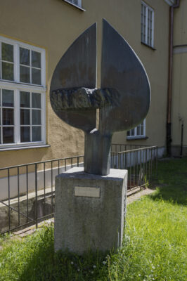 Zdjęcie pionowe wykonane na wprost, na którym znajduje się rzeźba o abstrakcyjnym charakterze wykonana w brązie. Na jej konstrukcje składają się dwa wydłużone półkola, zwrócone ku sobie swoimi średnicami. Na ich dolnych częściach został umieszczony element przypominający zminiaturyzowany tłum ludzi, których ciała zaczynają zlewać się w jedną masę. Cała kompozycja została ustawiona na niskim walcu. Rzeźba znajduje się na kamiennym, jasnoszarym, sześciennym postumencie, na którego jednej ze ścian znajduje się plakietka z napisem: „Kosynierom Gdyni. Zbigniew Zabrocki”.