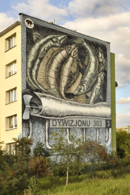 Zdjęcie pionowe przedstawiające boczną ścianę wielokondygnacyjnego budynku mieszkalnego, której powierzchnia została pokryta muralem przedstawiającym otwartą do połowy konserwę rybną. W środku znajdują się ułożone obok siebie ryby, które sprawiają wrażenie hybryd zwierząt i robotów. Estetyka muralu utrzymana jest w konwencji sztuki komiksowej, zaś jego kolorystyka jest zimna, zdominowana przez szaro-błękitną tonację. Pod zwiniętym w rulon wiekiem konserwy artysta umieścił napis: „Dywizjonu 303 3”.